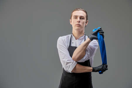 Portrait of a male chef holding a tea towel over gray background. Copy space.の写真素材