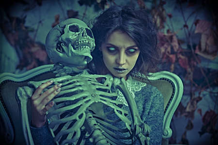 A frightening pale ghost girl with dusty black hair and colourless eyes looking agressively at the camera. Ruined vintage background. Halloween. Horror.の写真素材