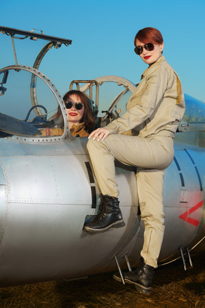 Professional commercial pilots women dressed in uniform and sunglasses pose sitting in their aircraft cockpit before taking off. Women in aviation.の写真素材