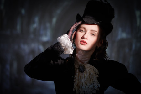 Vintage portrait of a beautiful lady in an elegant dress and a hat standing on a background of an...