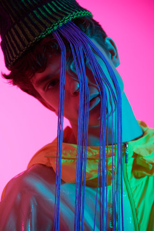 Youth style and creative designer clothes. Cool guy poses in a bright yellow jacket and a green hat...
