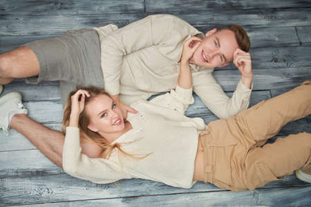 Portrait of a happy smiling carefree young couple spending free time together lying on the floor. Happy people.の写真素材