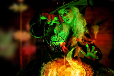 Scary Halloween tales. Portrait of a dangerous and frightening witch brewing a potion in her cauldron in a dark lair.の写真素材