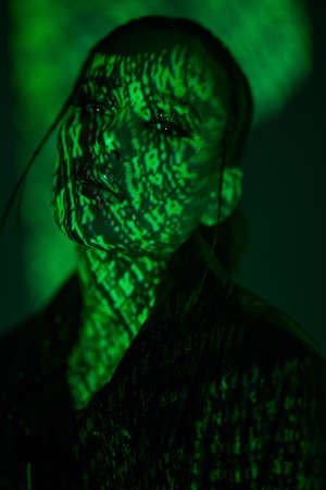 Futuristic style and beauty. Portrait of a gorgeous brunette girl in green light and shadows of the matrix. Cyber technology concept.の写真素材
