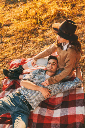 Romantic young couple enjoys a wonderful sunny day having a rest on a blanket by the river. Love concept. Autumn season.の写真素材