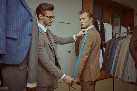 Prosperous young businessman getting the service of suit tailoring in a premium men's clothing store. Men's business fashion.の写真素材