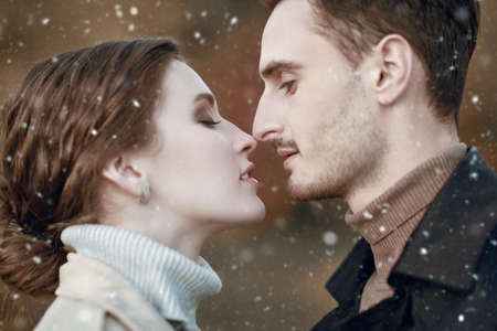 People in love. Beautiful happy loving couple in stylish clothes is going to kiss each other on a snowy winter day. Close up portrait. Winter season.の写真素材