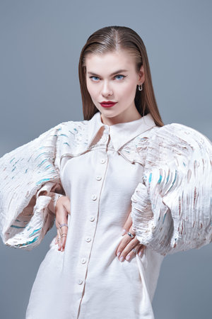 Haute couture fashion. Gorgeous young woman fashion model poses in extravagant beige blouse with...
