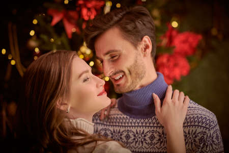 Beautiful happy girl and young man hugging each other and laughing in a beautiful room decorated for Christmas. Happy loving couple. Merry Christmas and Happy New Year!の写真素材