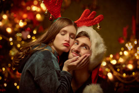 Happy beautiful people in love hug and enjoy each other celebrating Christmas in beautiful cozy atmosphere of a home decorated with lights. Happy family on Christmas. Festive Christmas decorations.の写真素材