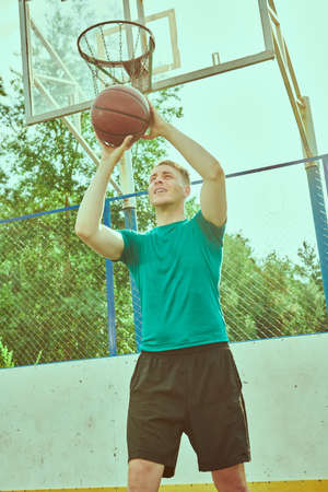 Handsome young man having basketball practice outdoor.の写真素材