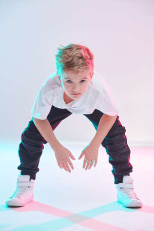 Modern handsome boy breakdancer in a white t-shirt, sweatpants and sneakers posing at the studio on a white background. Full length portrait. Kid's fashion. Sports and activities.の写真素材