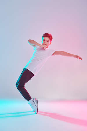 Contemporary dances. Professional hip hop and break dancer boy dancing at studio on a white background in mixed colored light. Full length portrait.の写真素材