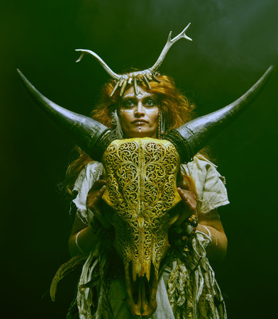 Female shaman in an ethnic dress doing a mysterious ritual with an animal skull. Studio portrait on...