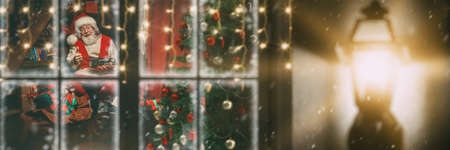 Festive Christmas and New Year preparations. Portrait of good old Santa Claus preparing gifts for children at his home. Spying on Santa Claus through the window. Christmas tale.の写真素材