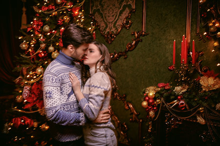 Happy couple in love kiss on Christmas night standing in a beautifully decorated room on Christmas....