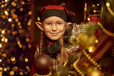 Christmas tale. A funny and cheerful girl elf stands in a fabulous Christmas setting and smiles...