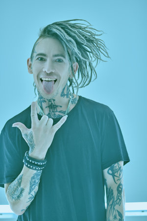 Youth alternative culture. Handsome punk rock musician with cool dreadlocks and tattoos poses...