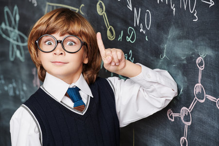 Education. Portrait of a cute smart boy in neat school uniform wearing glasses standing at the...