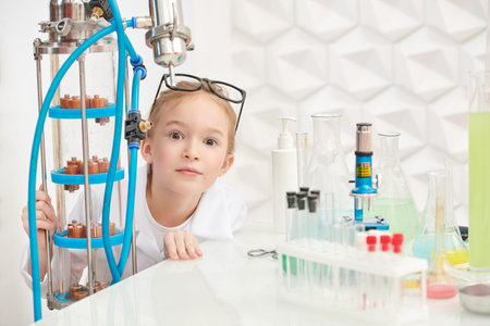 Funny little girl is doing experiments in the laboratory and is surprised. Science and education.