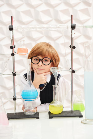 Early development of children. A smart little boy in neat school uniform is making science...