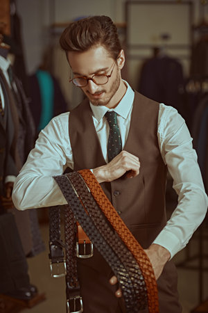 Portrait of a respectable young brunet man dressed in a smart brown suit standing in a men's...