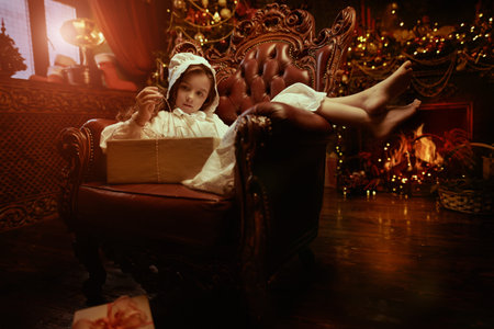 Christmas wishes and dreams. Portrait of a little girl in a nightie,  sitting in a vintage armchair...