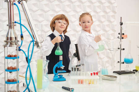 Two children scientists pose proudly with agents making experiments in the laboratory. Educational concept. Early development of children.の写真素材