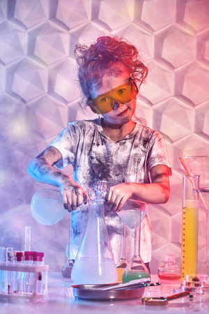 Science experiments and children. A cute smiling girl with goggles and matted hair conducts chemical experiments in the laboratory. Educational concept.の写真素材
