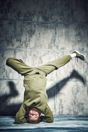 Full length portrait of a boy dancing break dance in the studio on a grunge background. Contemporary...