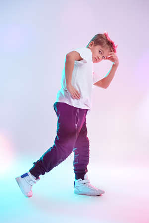Modern dances style. Cool breakdancer boy dancing in studio on a white background in mixed colored lighting. Hip-hop dancer. Sports and activities.の写真素材