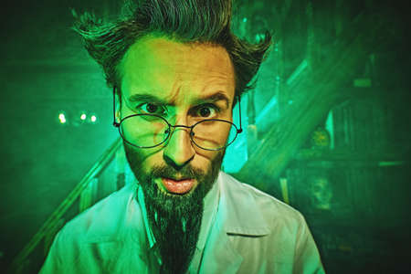 Portrait of a crazy scientist in his laboratory, lit by a mysterious green light. Character of a science fiction novel.の写真素材