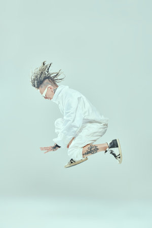 Full length shot of a modern punk rock musician with dreadlocks in white overall and stylish glasses...