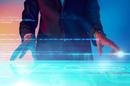 The business analyst manages business processes by touching a virtual screen with holographic charts and diagrams. Contemporary digital business technologies.の写真素材