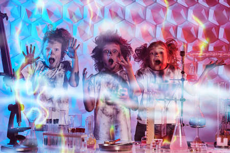 Group of kids with glasses and matted hair scream in a chemical laboratory after boom from an unsuccessful experiment. Science experiments and children.の写真素材