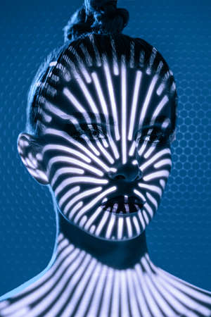 Close-up portrait of a fashion model girl with dark aggressive makeup posing in shadows. Studio shot on a blue background. Make up and cosmetics.の写真素材