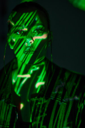 Cyber girl of the future. Portrait  of an attractive girl in black leather jacket lit by green neon light. The matrix style.の写真素材
