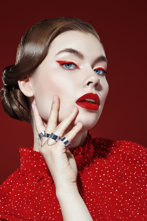 Portrait of a beautiful elegant woman with bright red arrows and red lipstick in a feminine red...