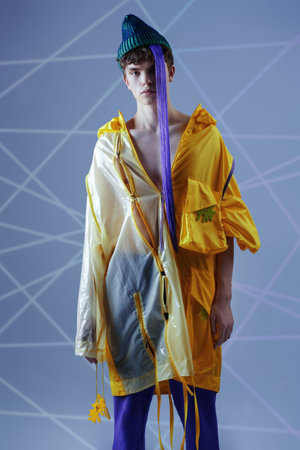 Youth style and creative designer clothes. Cool guy in a bright yellow jacket, purple sweatpants and...