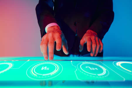 A man in a suit touches a digital virtual screen with holographic charts and diagrams. Modern virtual digital technologies. Business concept.の写真素材