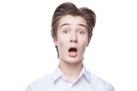 Portrait of a surprised teenage boy in a neat white shirt looking at the camera with his mouth open. Education. Clever children. White background. Close up shot.の写真素材
