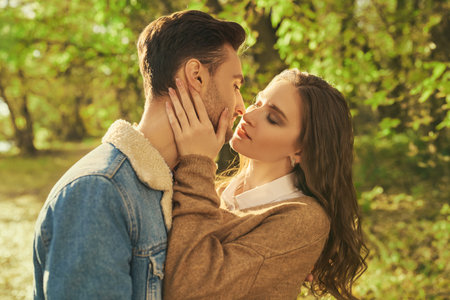 A beautiful loving couple in autumn denim clothes kissing in an autumn park on a nice sunny day....