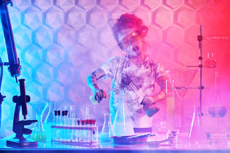 A funny girl with goggles and matted hair conducts chemical experiments in the laboratory. Educational concept. Science experiments and children.の写真素材
