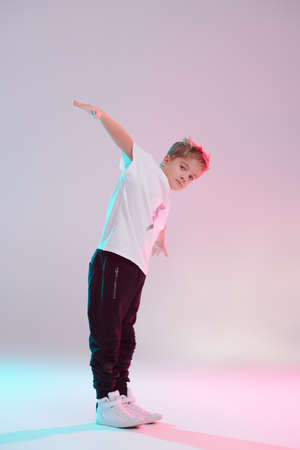 Modern dances style. Cool breakdancer boy dancing in studio on a white background in mixed colored lighting. Hip-hop dancer. Sports and activities.の写真素材