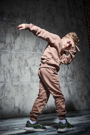 Contemporary dances. Boy dancing break dance in the studio on a grunge background. Sports and active lifestyle. Full length portrait.の写真素材