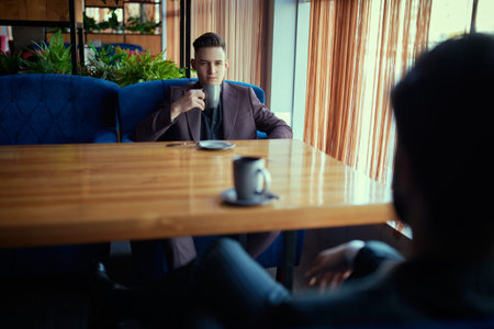 Two serious businessmen have a business meeting concerning the details of a deal while drinking...