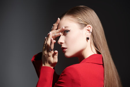 Fashion and jewelry. Beautiful young girl with elegant makeup and jewelry posing in a bright red...