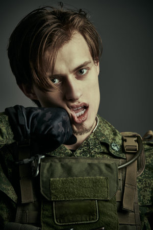 Portrait of a furious courageous soldier in camouflage who is hit in the face with a fist. War,...