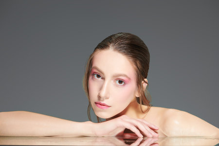 Health and beauty concept. A beautiful model girl with soft pink makeup poses bending down over...