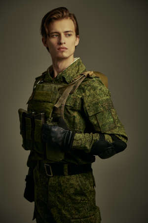 Portrait of an Army soldier in Protective Combat Uniform on a khaki background. Military concept. Studio shot.の写真素材